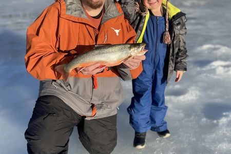 Ice fishing on frozen water with local guide