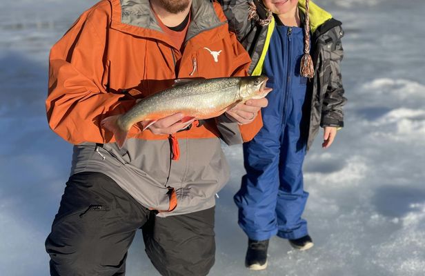 Ice fishing on frozen water with local guide